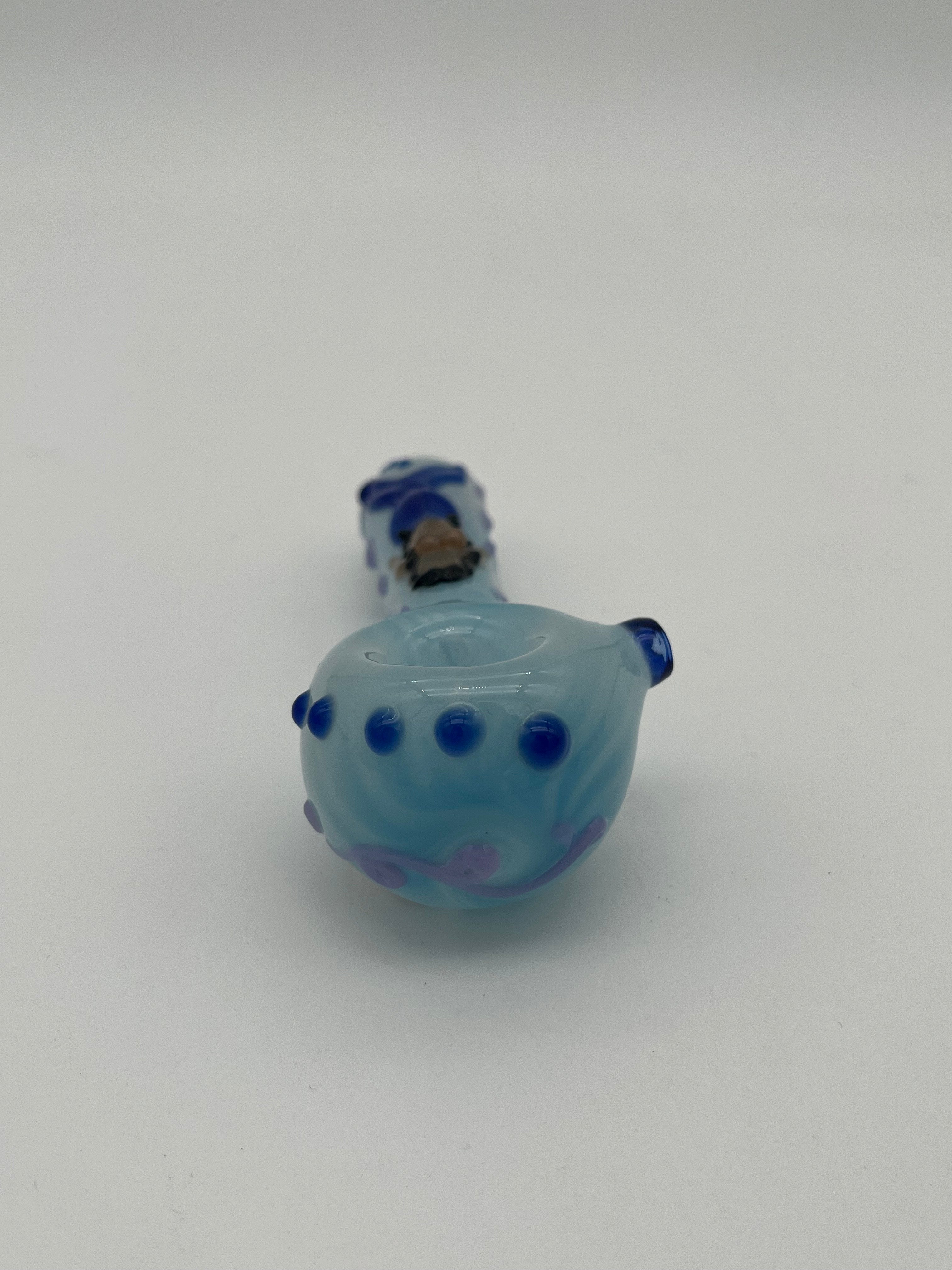 Light blue glass pipe with blue accents  and a mermaid on the top of it made by Kristi Conant on a white background
