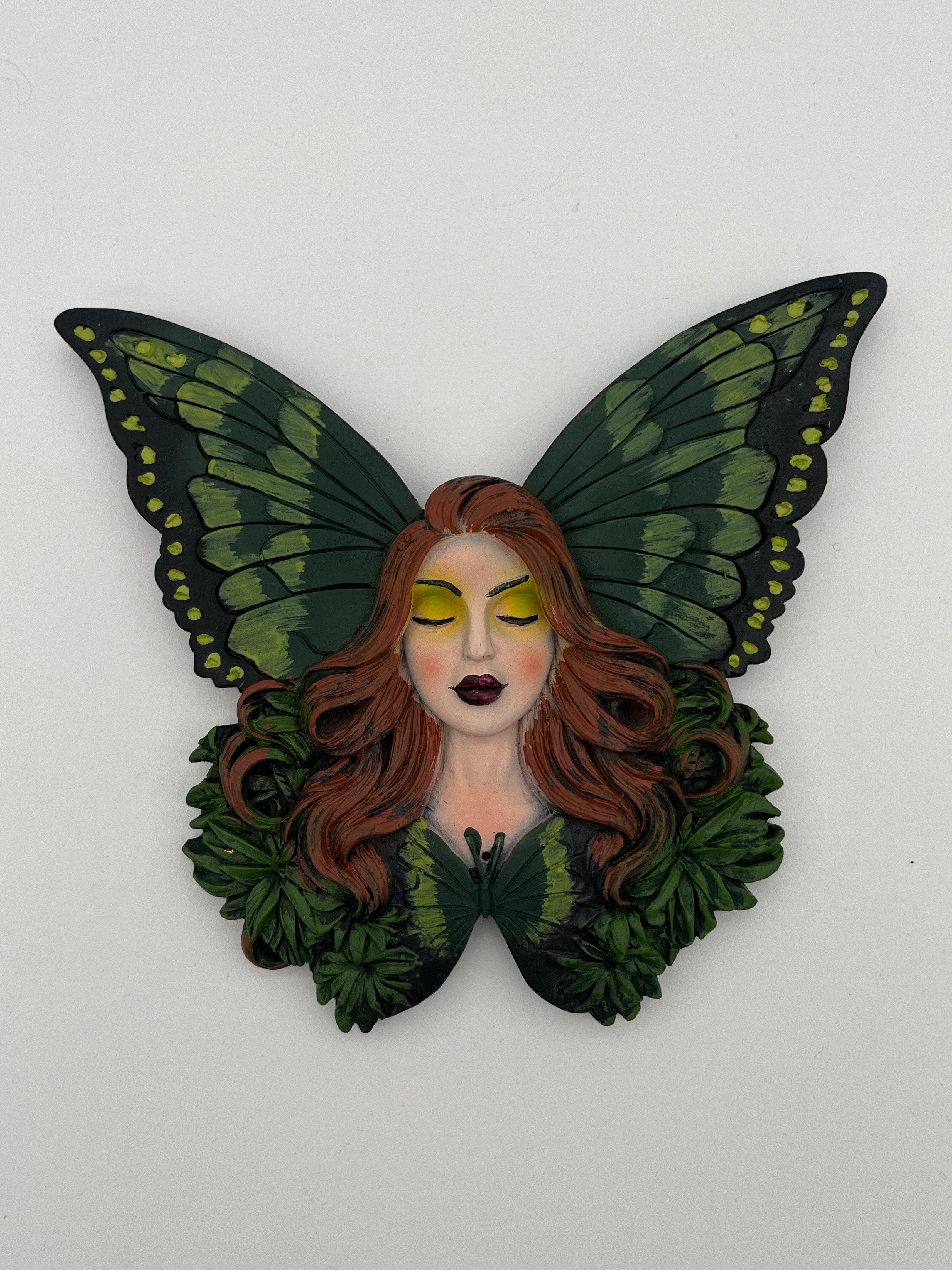 Butterfly-shaped figurine with a face on a white background