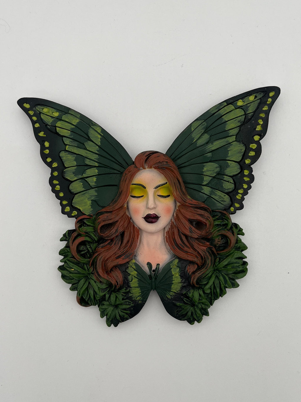 Butterfly-shaped figurine with a face on a white background