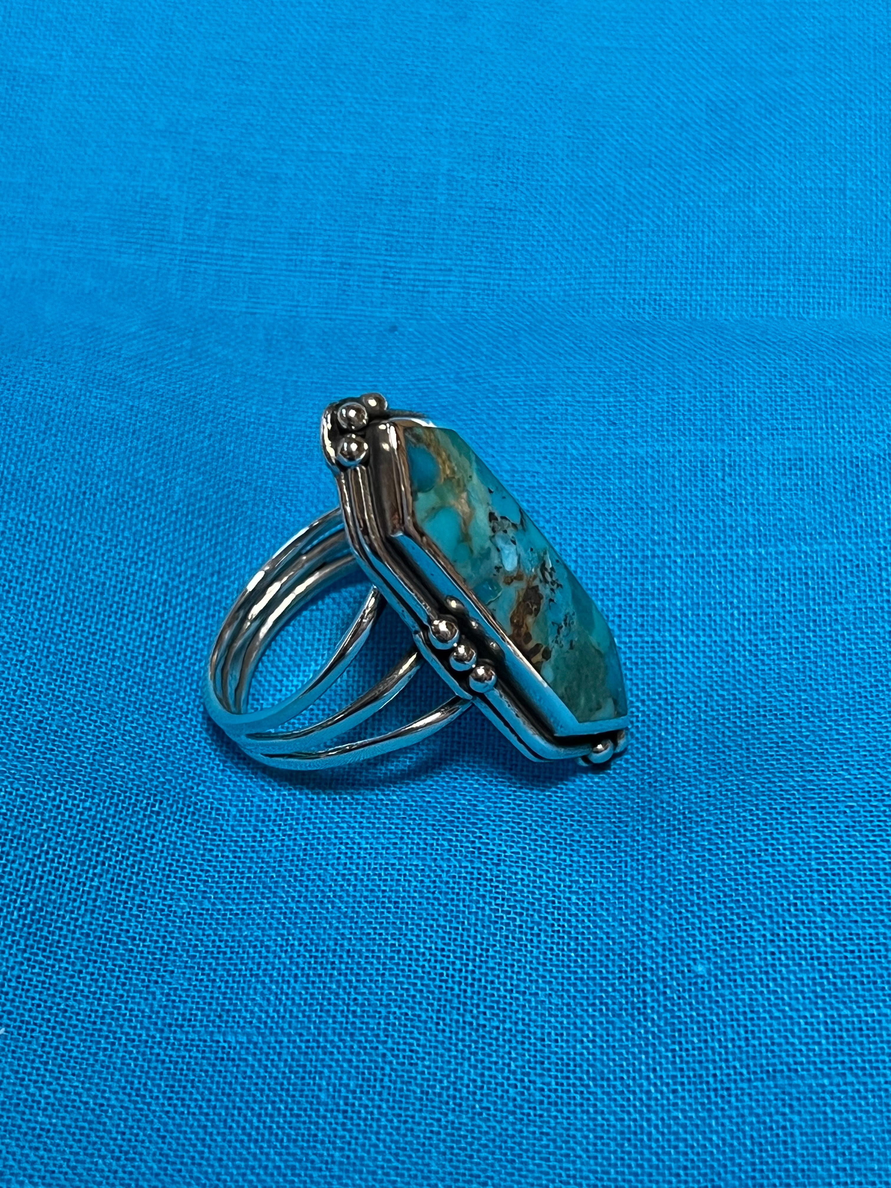 Silver ring with a turquoise stone on a blue fabric background