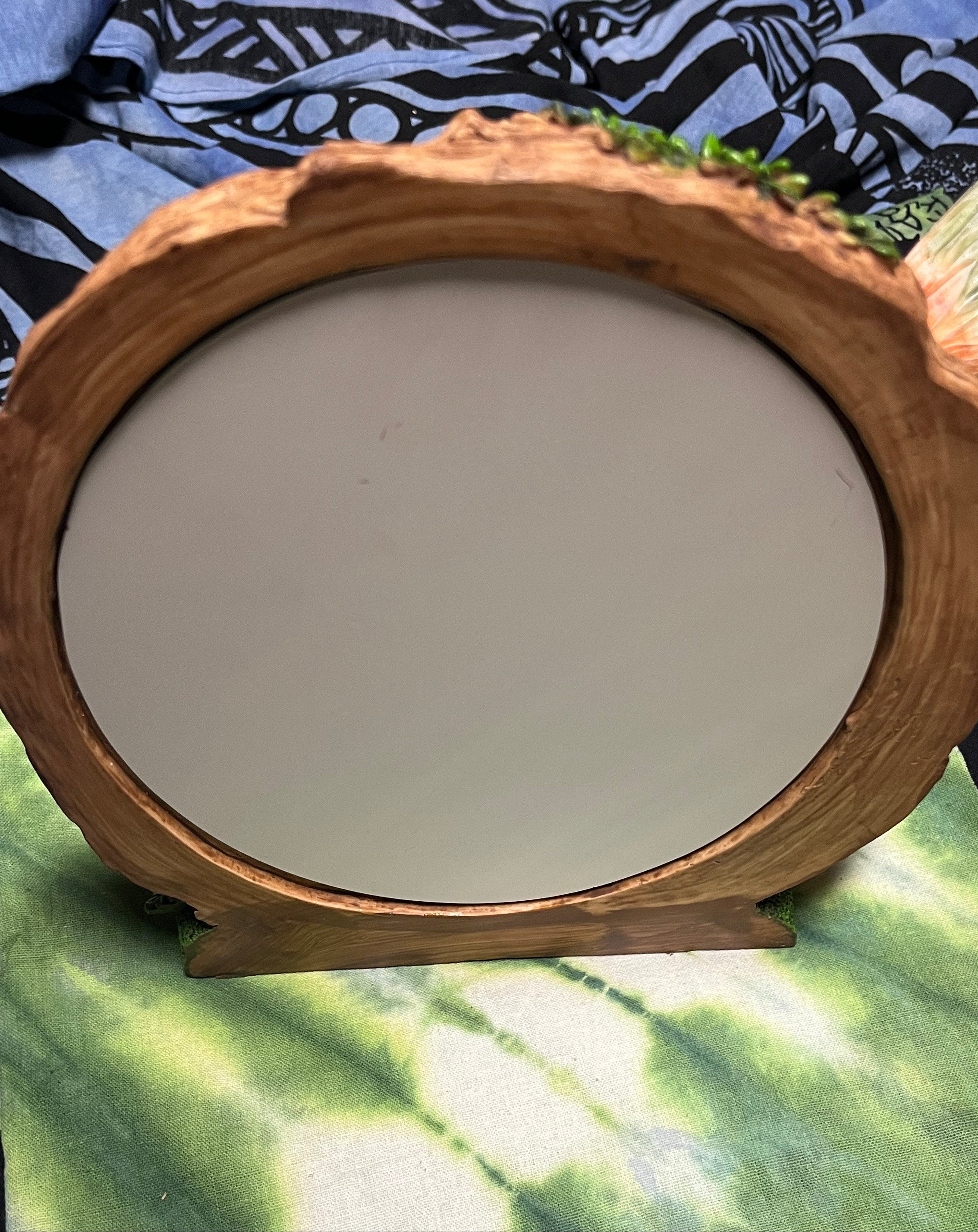 Wooden-framed mirror on a colorful fabric background